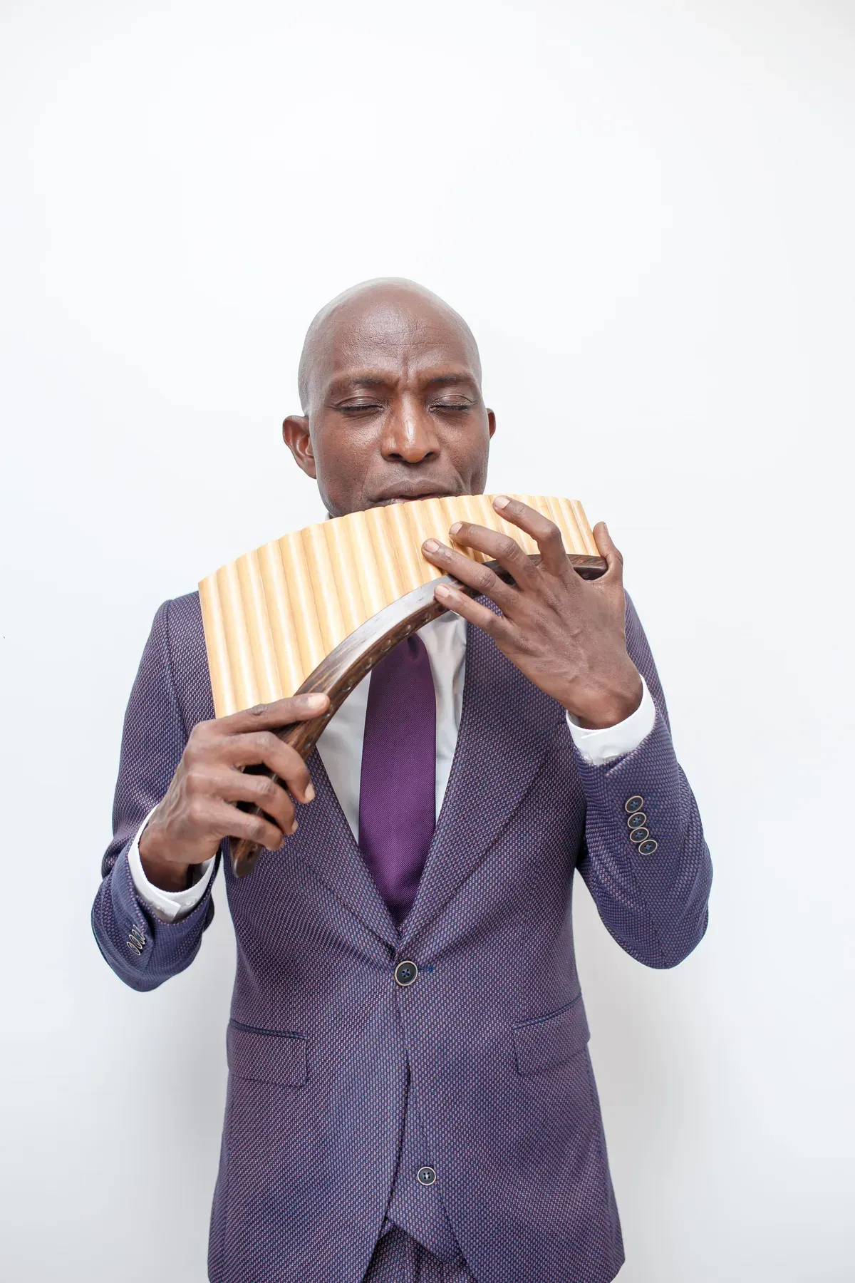 Richard Meseko playing the pan flute in a suit.