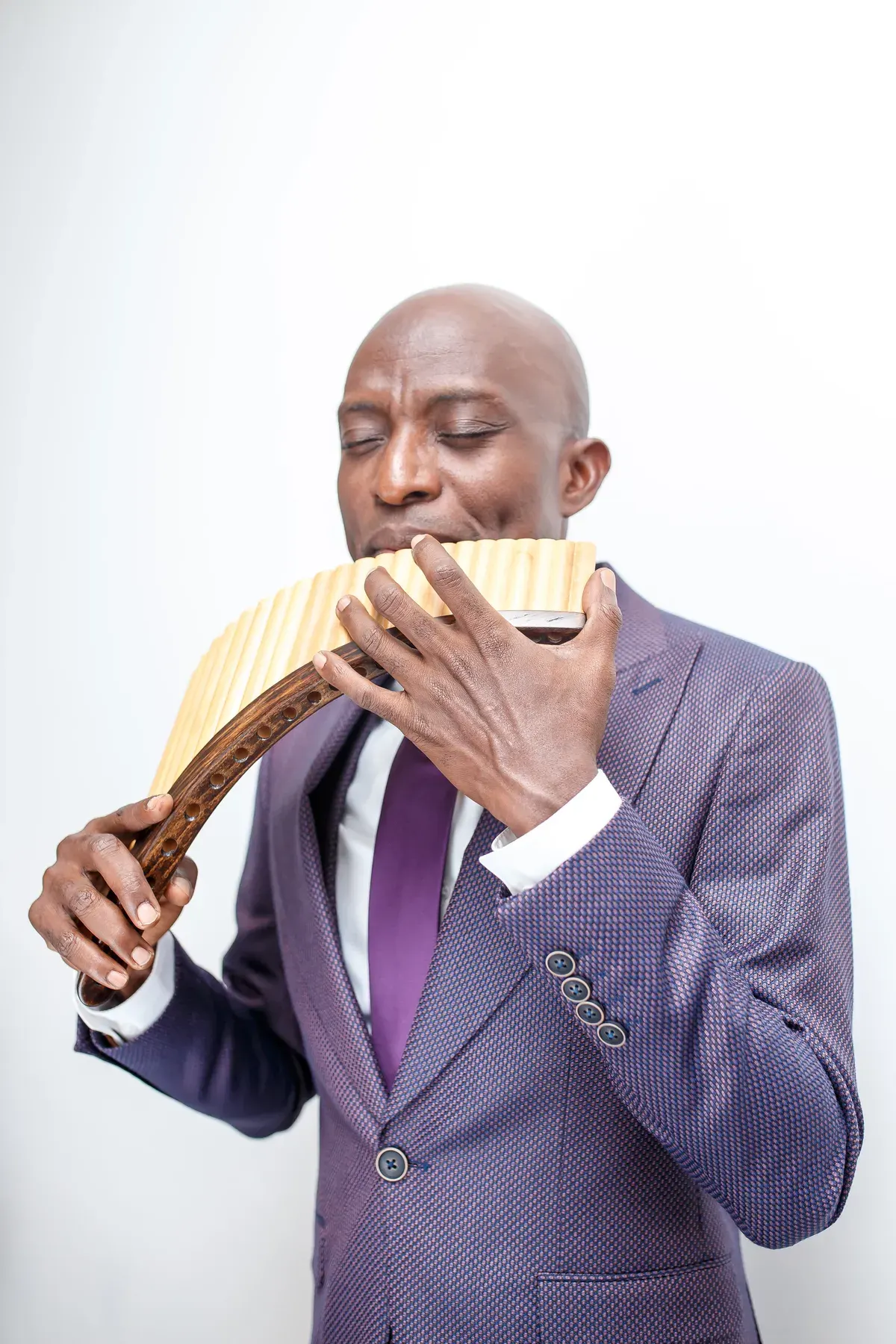 Richard Meseko holding a pan flute to his lips.