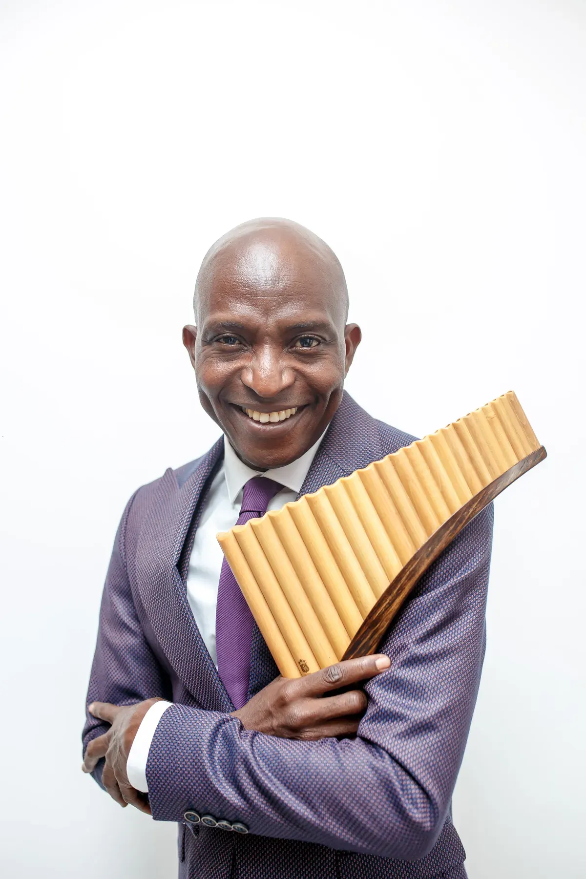 Richard Meseko smiling, holding the pan flute against his chest.