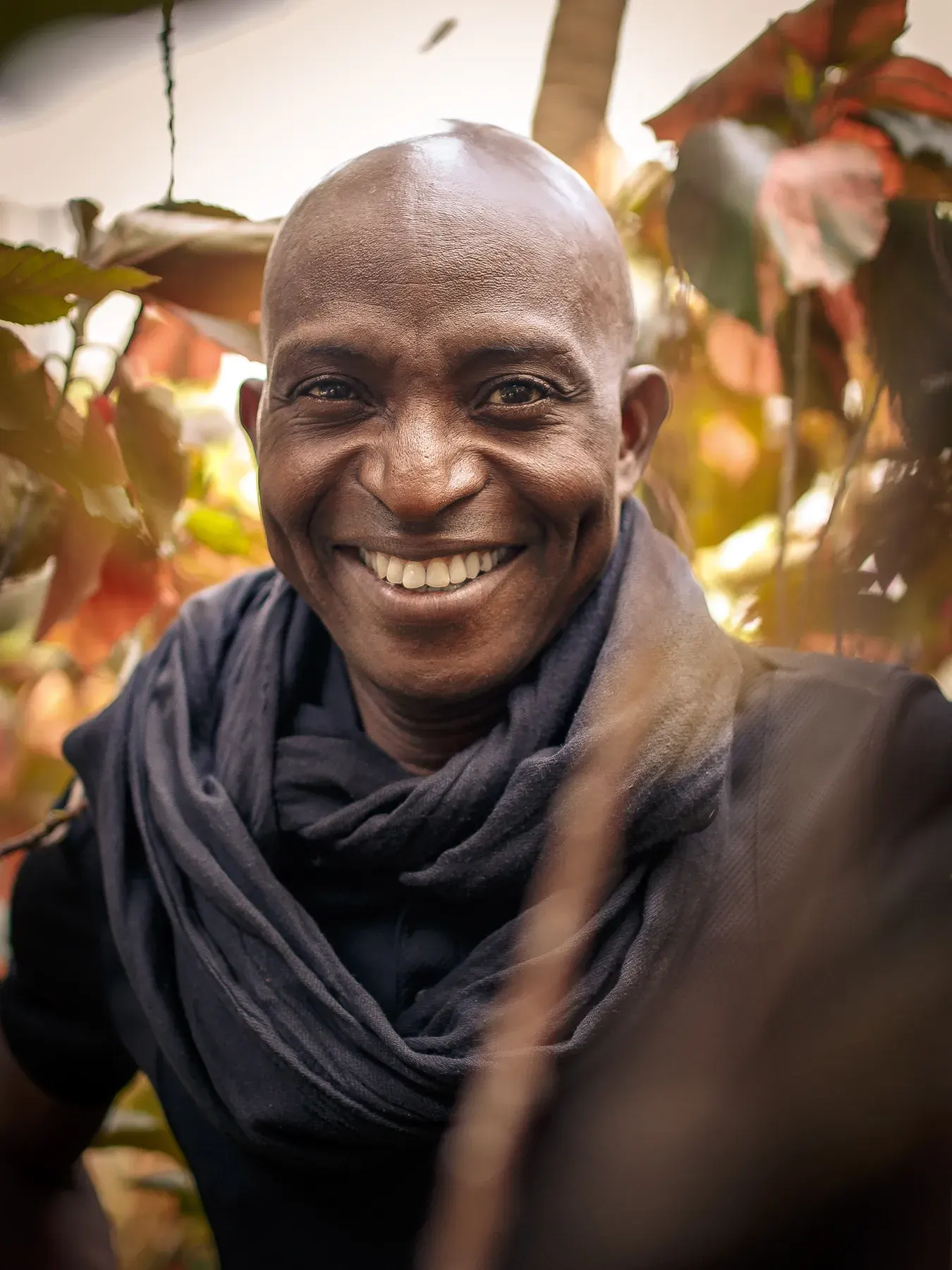 Richard Meseko laughing among leaves in a garden.